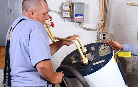 man in work uniform working on water heater