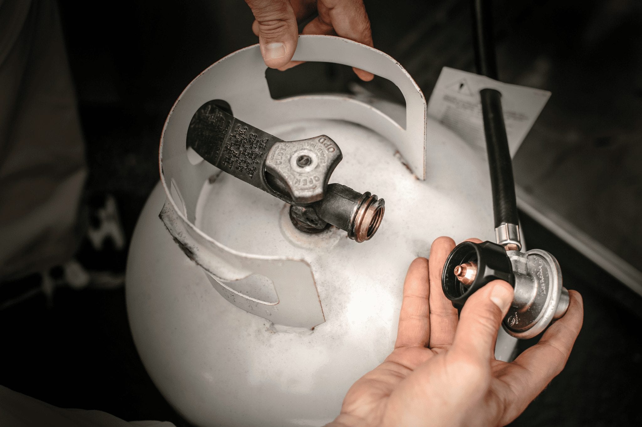 hands checking propane tank for leaks